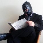 Executivo fetichista com máscara de latex lendo "Business Fetish Generation"