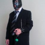 Executivo fetichista usando máscara, correntes e segurando gagball